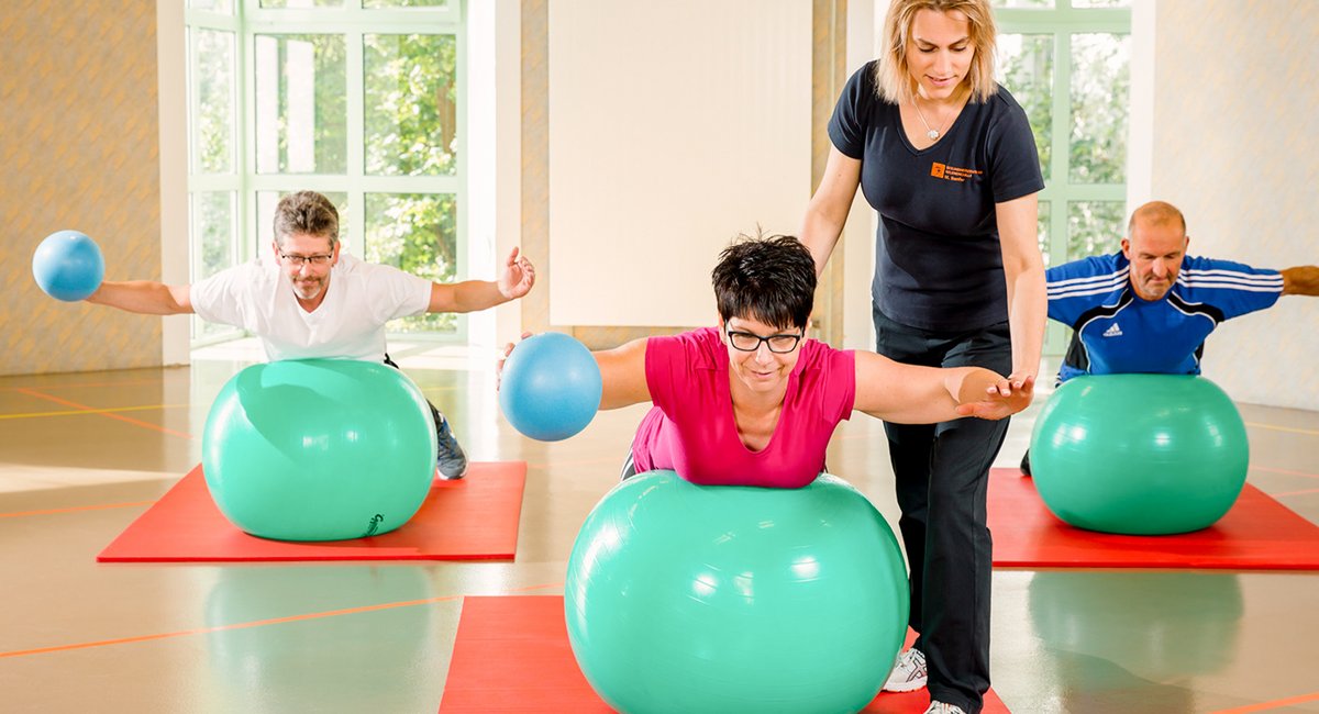 Trainerin führt Ballgymnastik mit einer Gruppe von Patienten durch