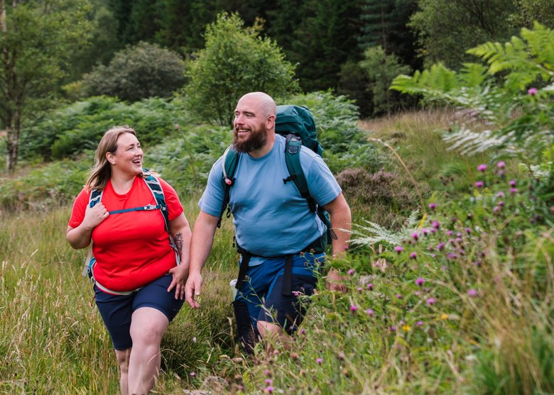 Mann und Frau wandern durch eine Wiesenlandschaft