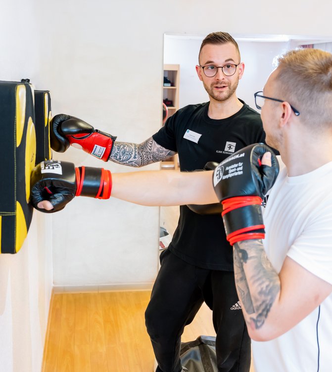 Zwei Männer boxen mit Boxhandschuhen auf ein Trainingsgerät