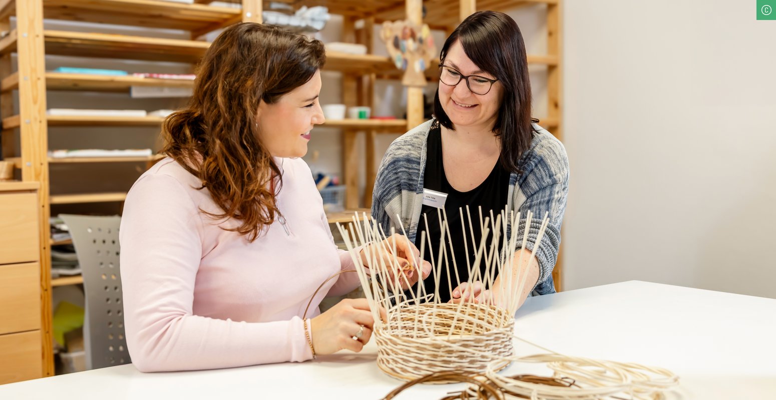 Zwei Frauen flechten zusammen einen Korb