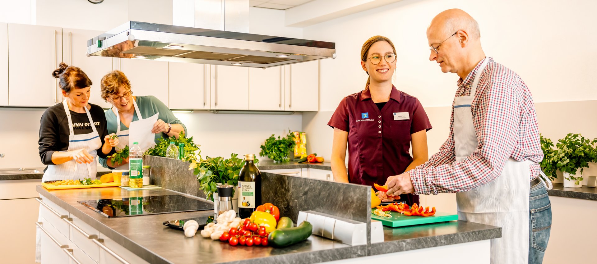 Gruppe steht um eine Kücheninsel und kocht