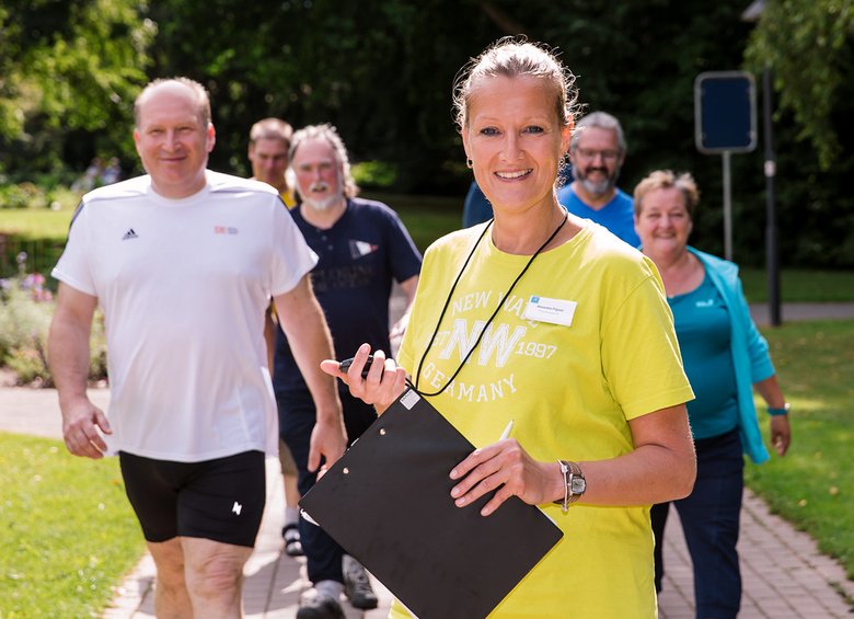 Frau mit Joggingruppe und einer Stoppuhr in der Hand